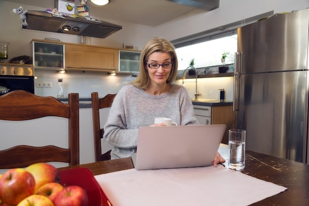 A person using a laptop while sitting at a kitchen table, surrounded by bills and financial documents, portraying the act of reviewing entitlements and planning for upcoming changes.
