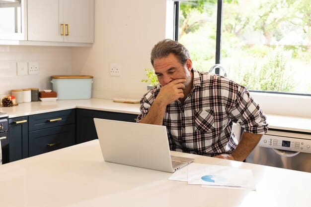 A person looking stressed while reviewing mortgage paperwork at their kitchen table, a laptop displaying fluctuating interest rates in the background. The image conveys the anxiety and potential challenges faced by mortgage holders due to interest rate variations.